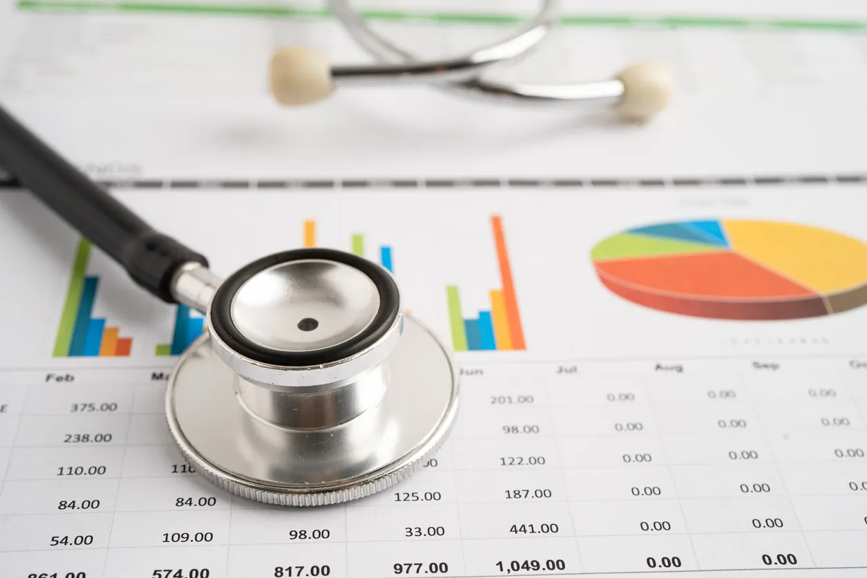 Stethoscope on revenue report with billing charts and cash flow data for ambulatory practice.