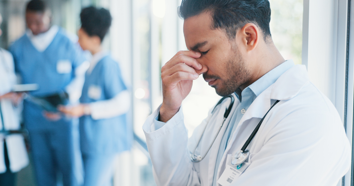 Physician experiencing burnout while managing heavy administrative workload in a busy medical office